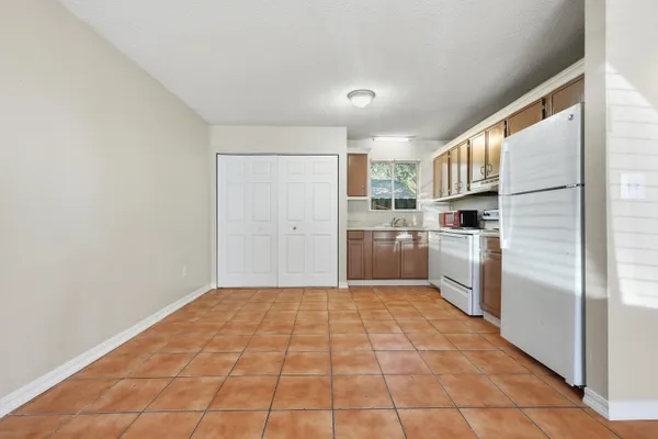 a kitchen with a refrigerator a stove top oven and white cabinets