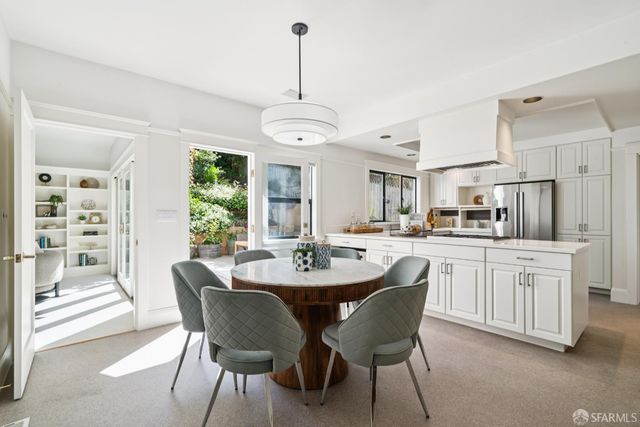 a kitchen with stainless steel appliances kitchen island granite countertop a dining table chairs and white cabinets