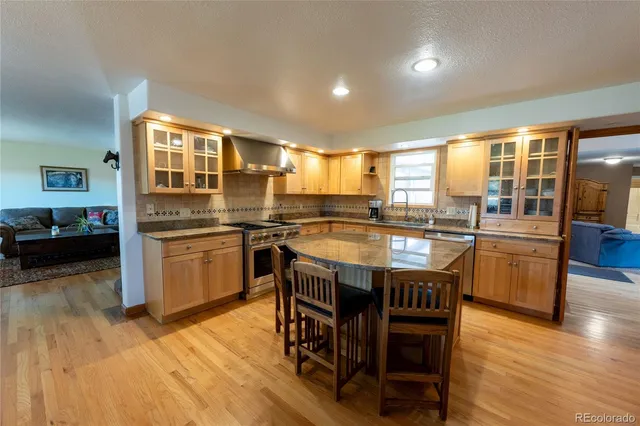a kitchen with granite countertop a stove a sink dishwasher and a dining table with wooden floor