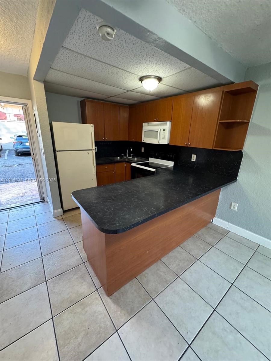 652 Northwest 3rd Street, Unit 104 Miami, FL 33128 - Photo 12 of 15 a kitchen with stainless steel appliances a sink a counter top space cabinets and a view of living room