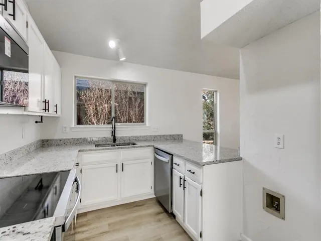 a kitchen with granite countertop a sink stove and cabinets