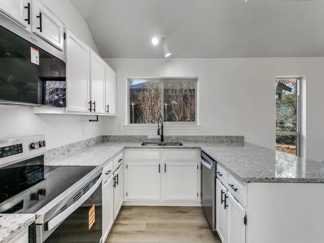 a kitchen with granite countertop a sink stove and cabinets