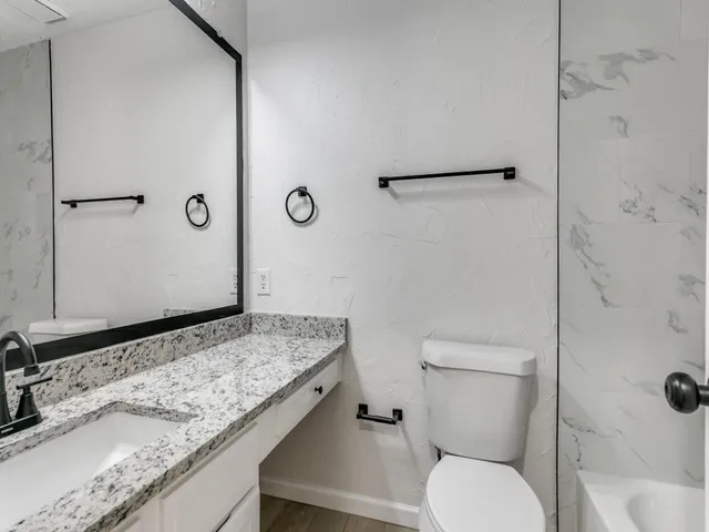 a bathroom with a granite countertop sink toilet and shower