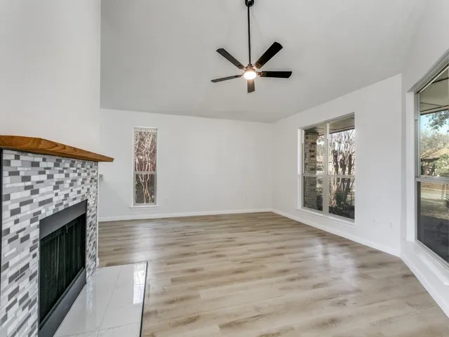 a view of an empty room with wooden floor fireplace and a window