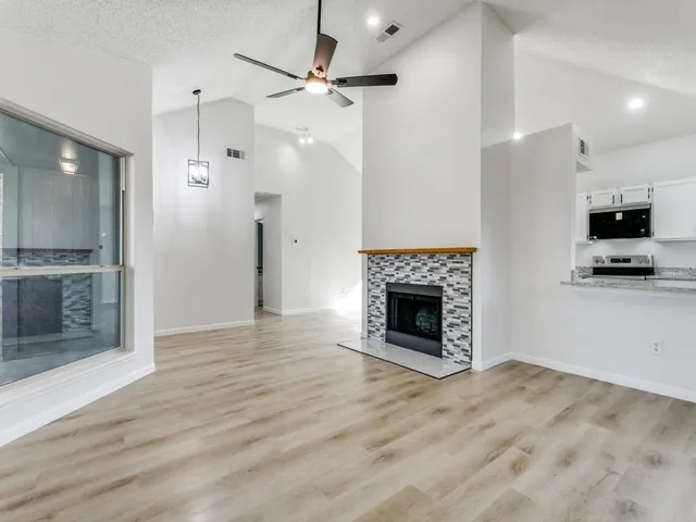 an empty room with wooden floor a fireplace and a ceiling fan