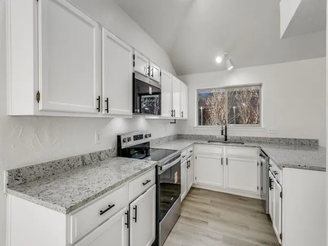 a kitchen with stainless steel appliances granite countertop a sink stove and cabinets