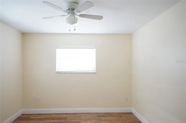 an empty room with a window and a ceiling fan