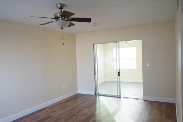a view of empty room with wooden floor and fan