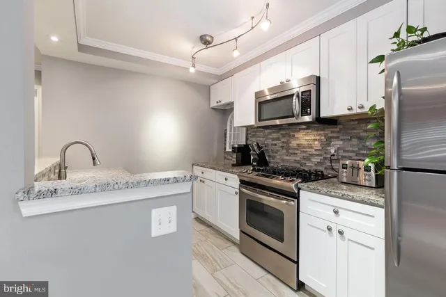 a kitchen with stainless steel appliances granite countertop a stove a sink and a microwave