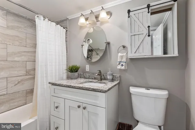 a bathroom with a granite countertop sink a toilet and a mirror