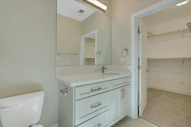 a bathroom with a granite countertop sink a toilet and a mirror