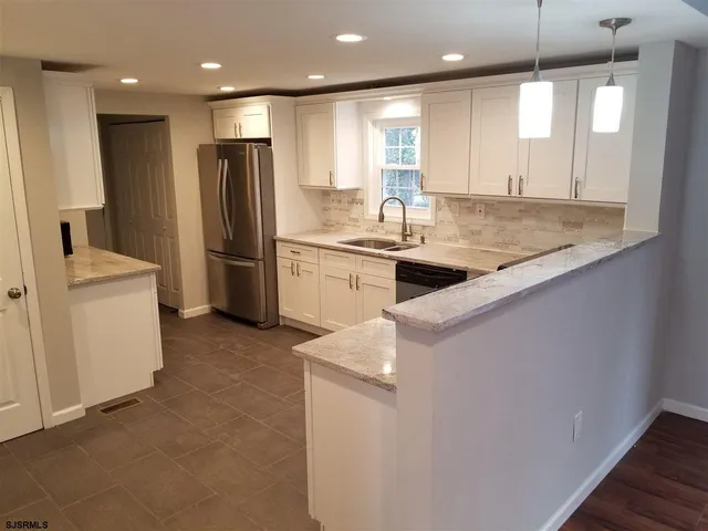 a kitchen with stainless steel appliances granite countertop a sink a stove and a refrigerator