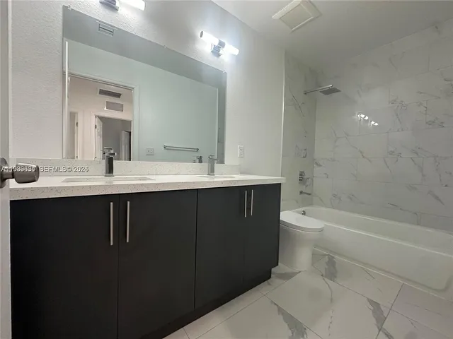 a bathroom with a bathtub sink vanity mirror and toilet
