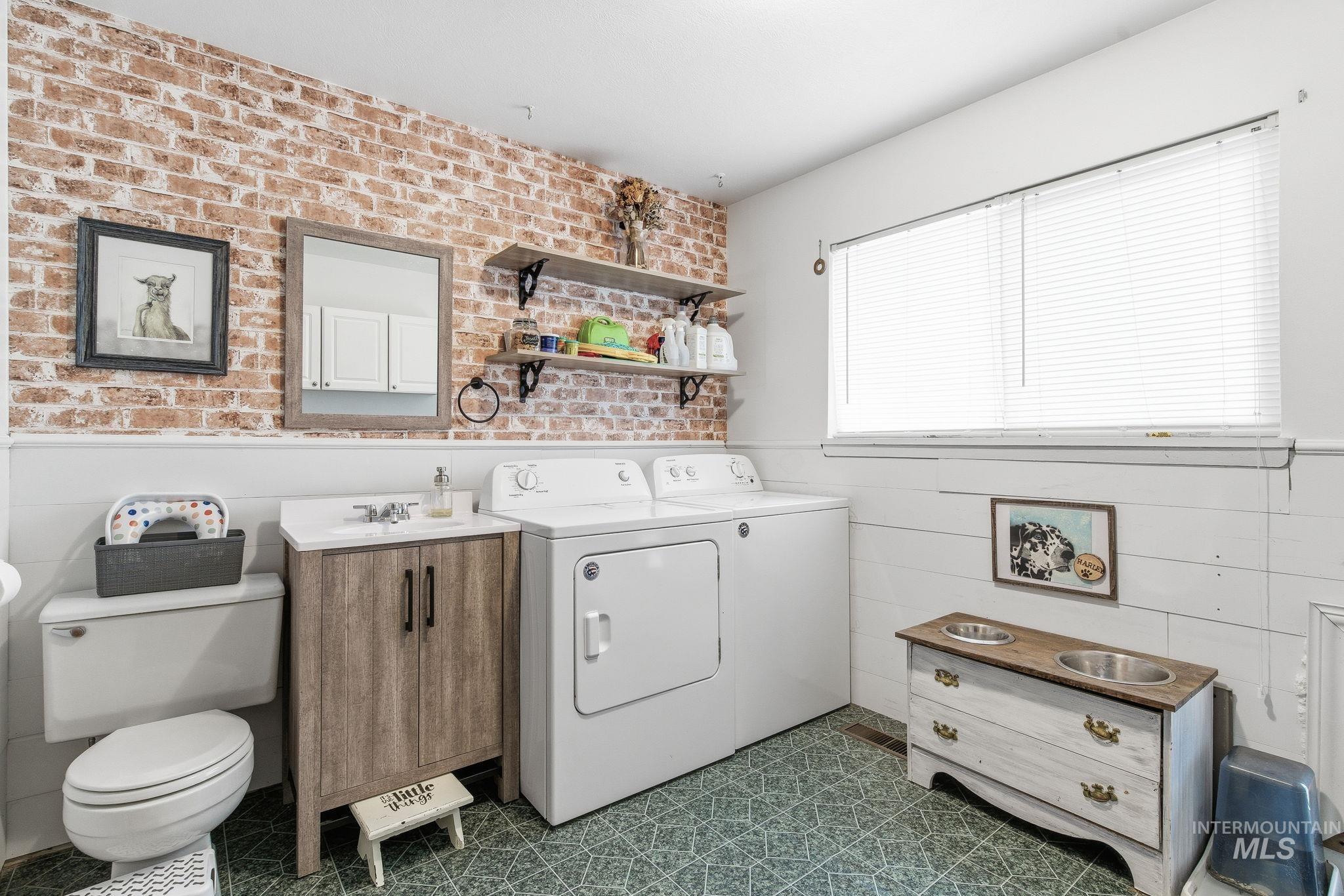 4426 West Clark Street Boise, ID 83705 - Photo 25 of 43 Laundry area with wainscoting, brick wall, washing machine and clothes dryer, and dark floors