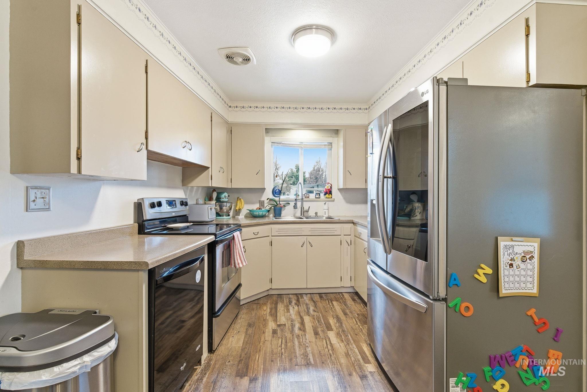 4426 West Clark Street Boise, ID 83705 - Photo 9 of 43 Kitchen with appliances with stainless steel finishes, light countertops, cream cabinets, light wood-style floors, and beverage cooler
