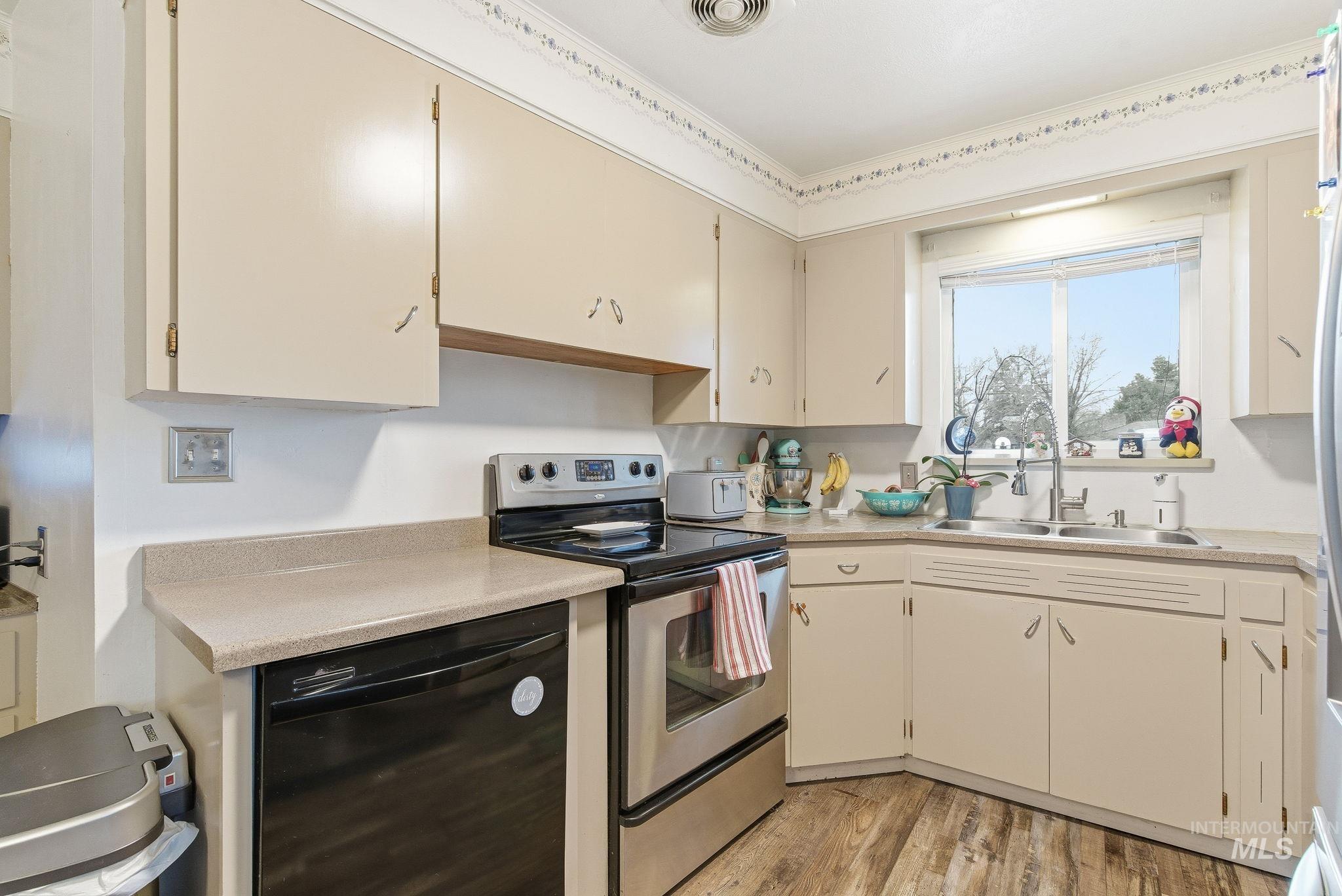 4426 West Clark Street Boise, ID 83705 - Photo 10 of 43 Kitchen featuring electric stove, light countertops, dishwasher, light wood-type flooring, and cream cabinets