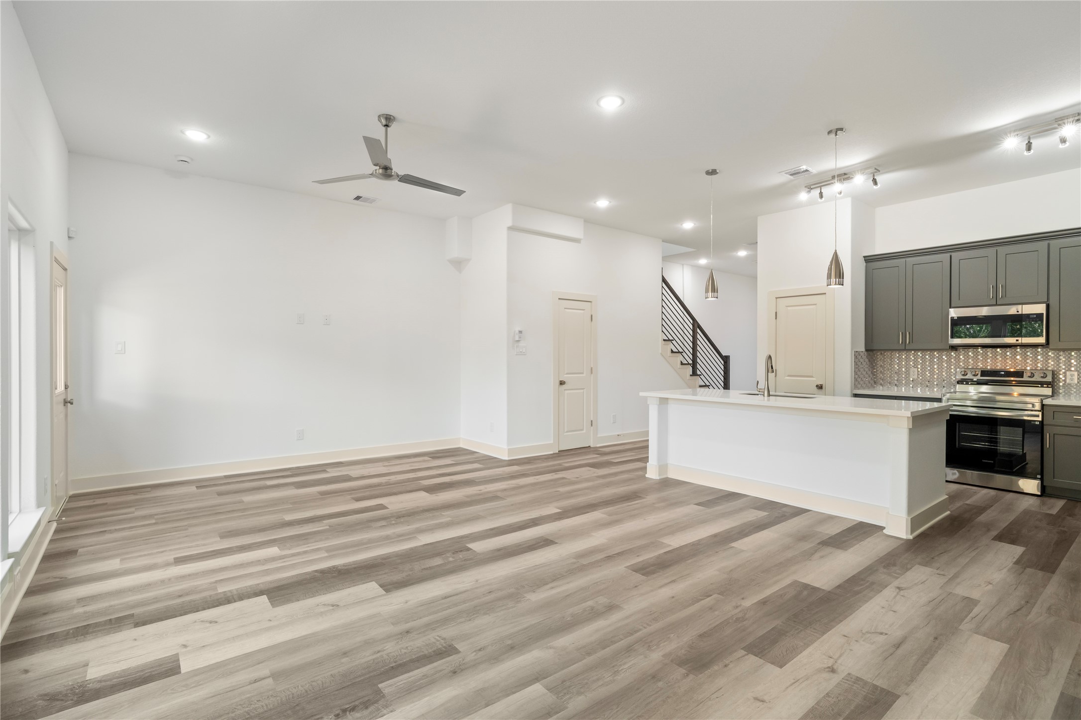 5629 Malmedy Road Houston, TX 77033 - Photo 17 of 24 Bright and spacious open-concept living area features sleek wood flooring and a modern kitchen with stainless steel appliances, a large island, and elegant cabinetry.