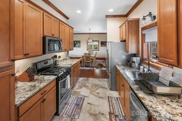 a kitchen with stainless steel appliances granite countertop a stove top oven a sink dishwasher a dining table and chairs with wooden floor