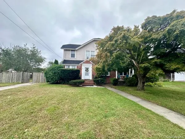 a front view of a house with a yard and trees