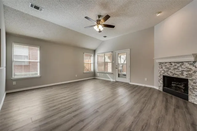 a view of an empty room with wooden floor fireplace and a window