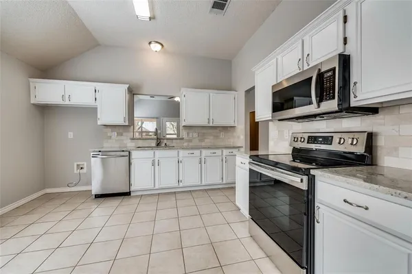 a kitchen with stainless steel appliances granite countertop a stove a sink and a microwave
