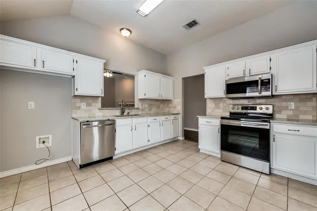 a kitchen with granite countertop white cabinets and stainless steel appliances
