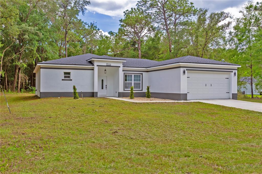 a front view of house with yard and trees in the background