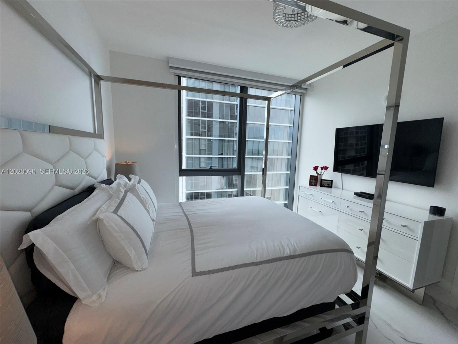 788 Northeast 23rd Street, Unit 1202 Miami, FL 33137 - Photo 32 of 64 a bedroom with a bed tv and a window