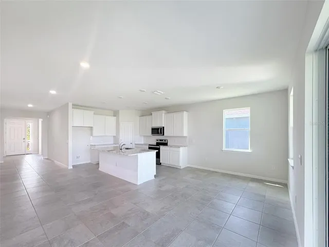 a large white kitchen with a stove a sink a refrigerator and a cabinets