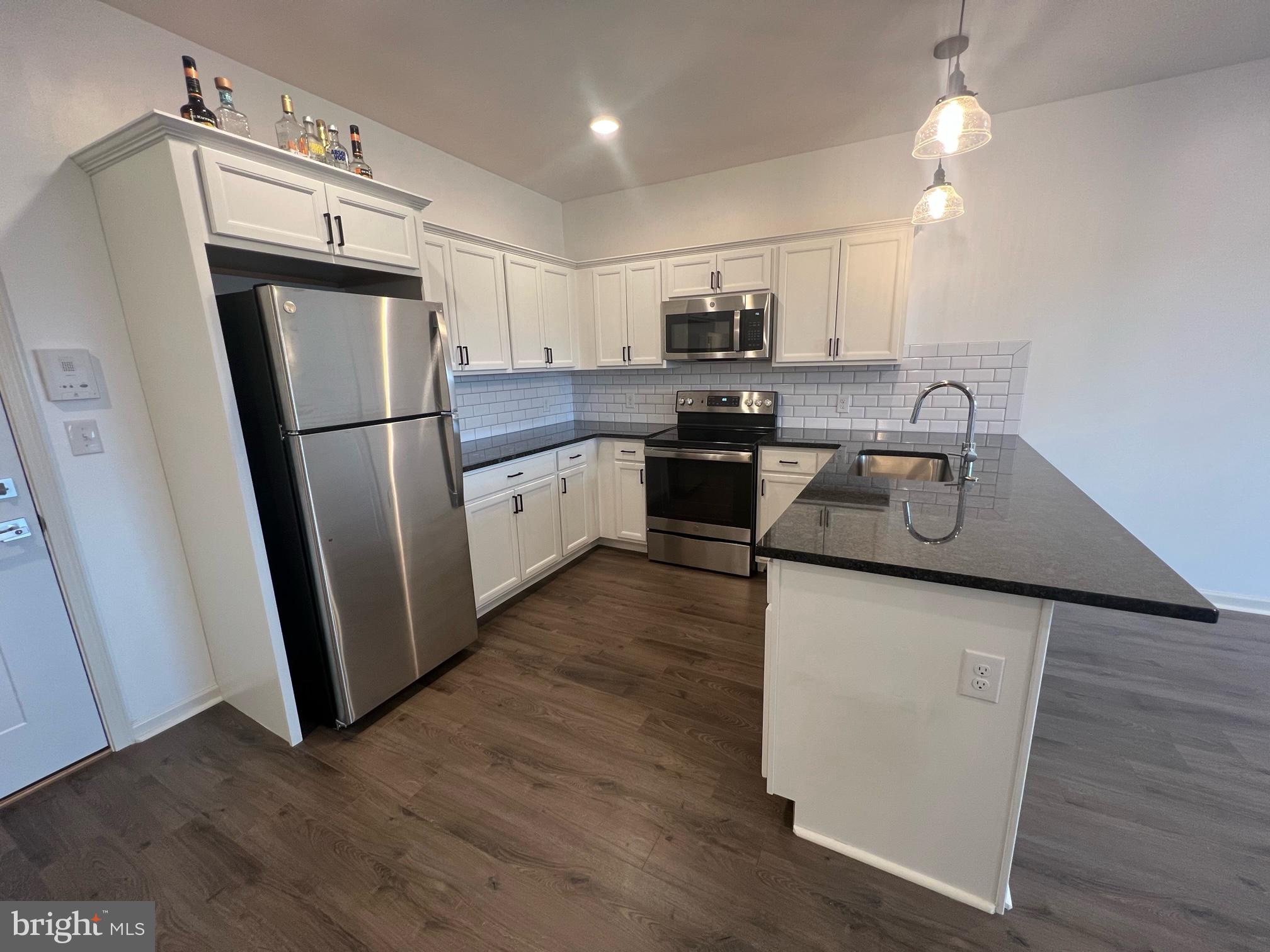 a kitchen with kitchen island wooden floors appliances and cabinets