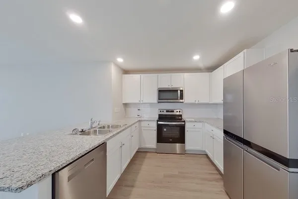 a kitchen with stainless steel appliances granite countertop a refrigerator a sink and a stove