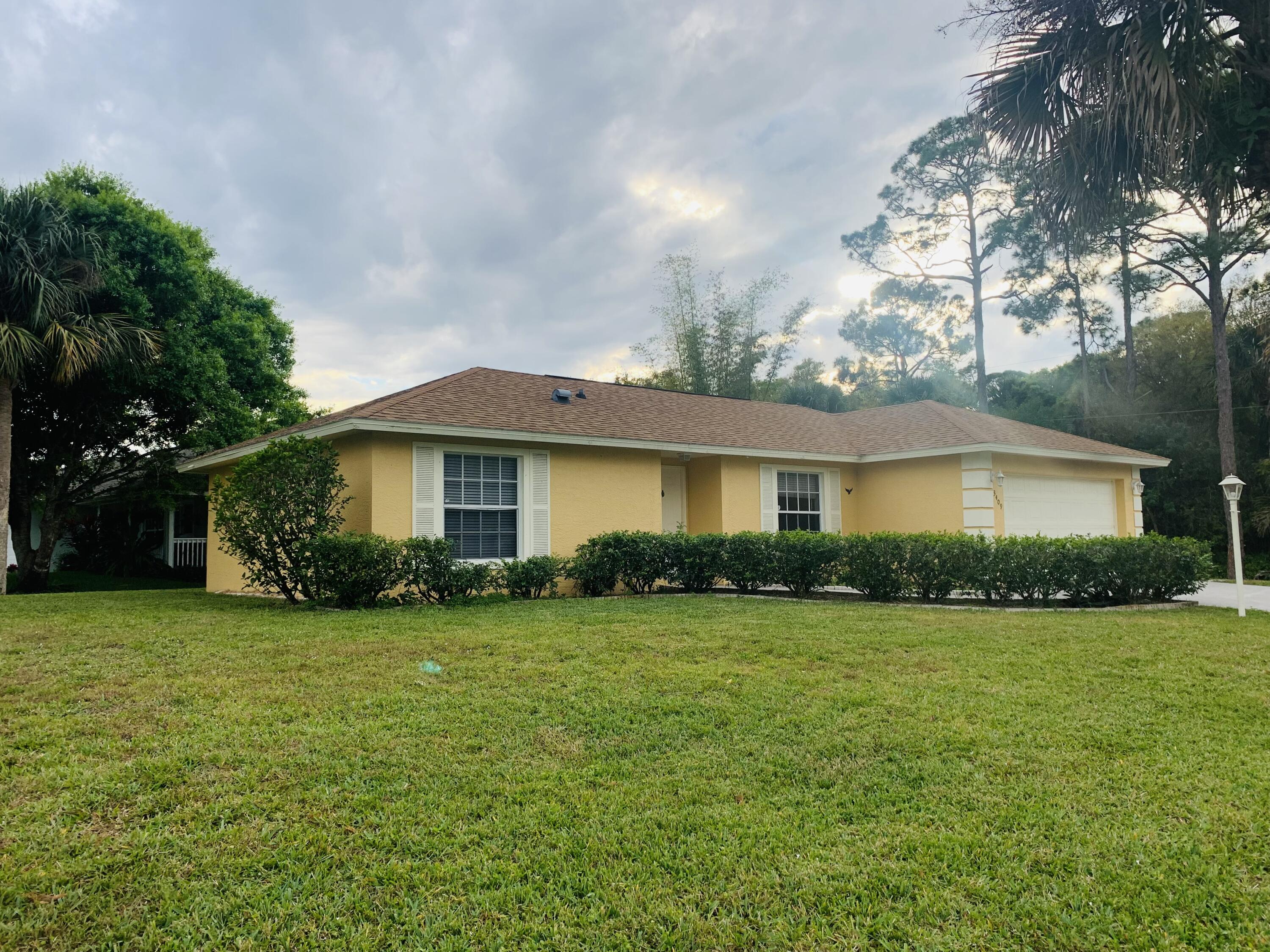 a front view of a house with a garden and trees