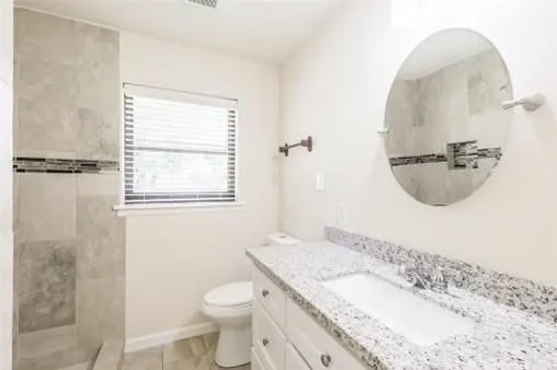 a bathroom with a granite countertop sink a toilet and a mirror