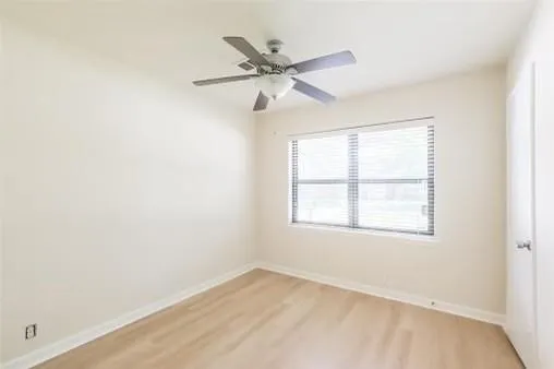 an empty room with a window and a fan