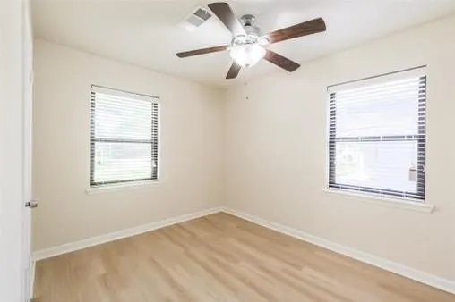 an empty room with a window and a fan