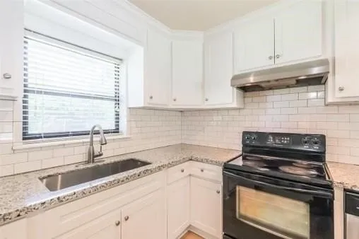 a kitchen with granite countertop a stove sink and cabinets