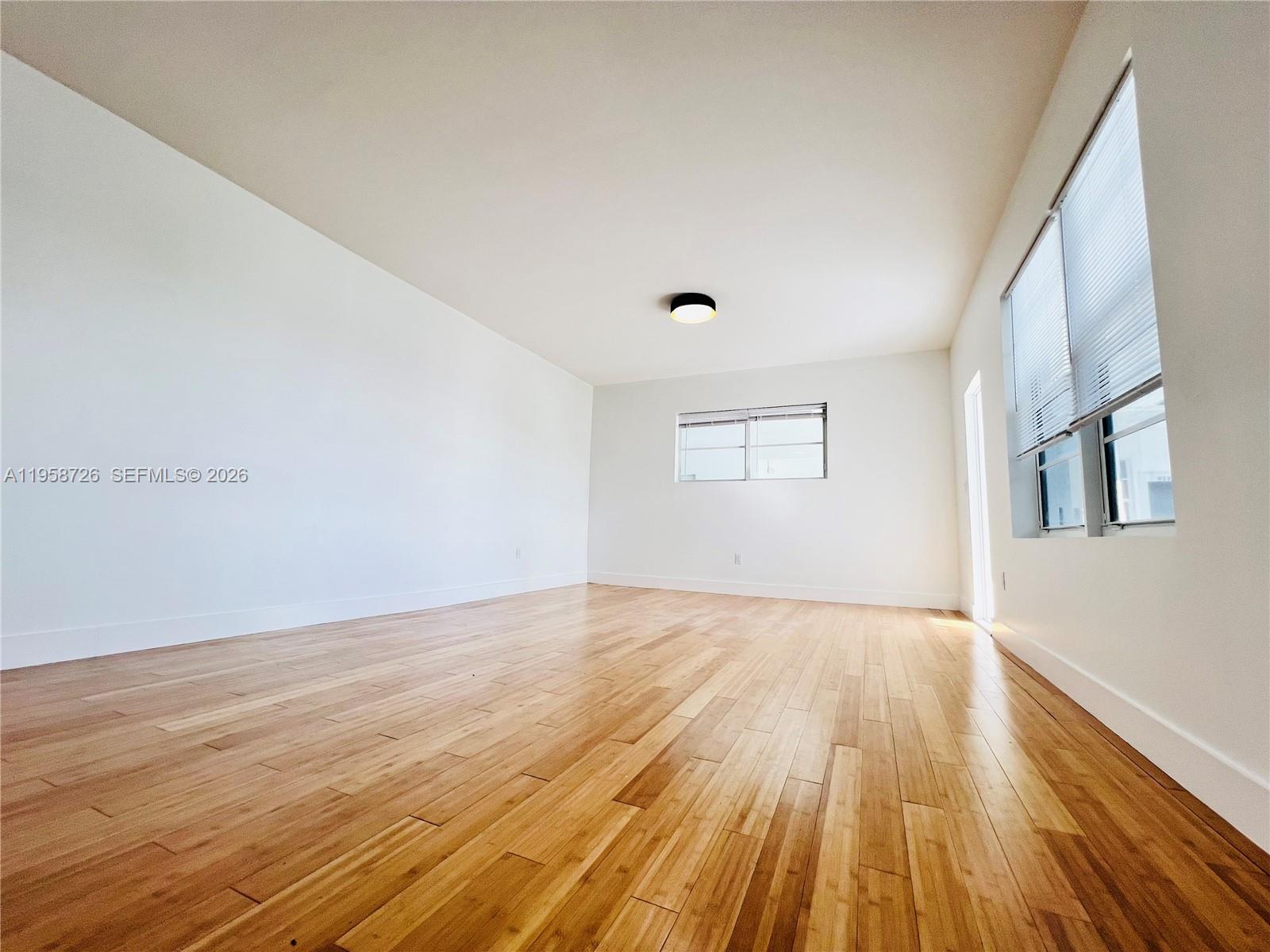 960 Bay Drive, Unit 902 Miami Beach, FL 33141 - Photo 14 of 25 a view of an empty room with wooden floor and a window