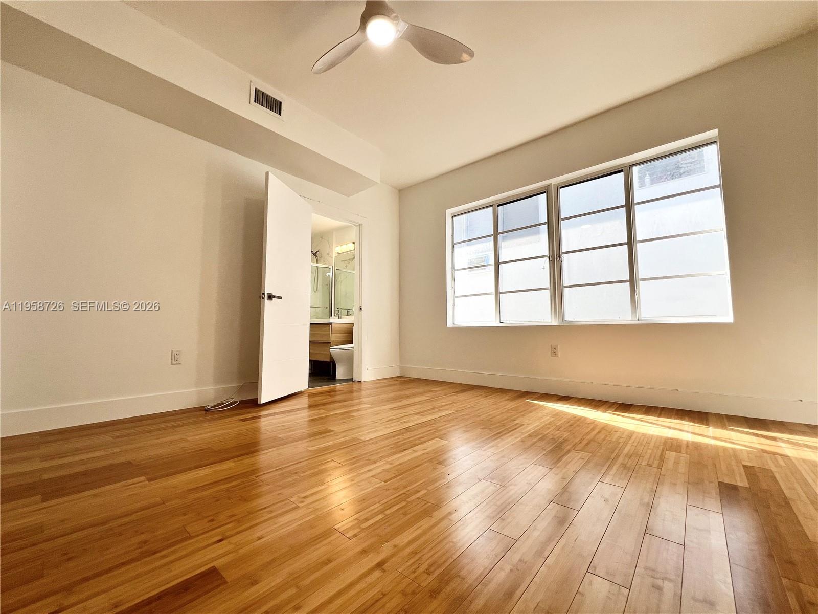 960 Bay Drive, Unit 902 Miami Beach, FL 33141 - Photo 17 of 25 an empty room with wooden floor and windows