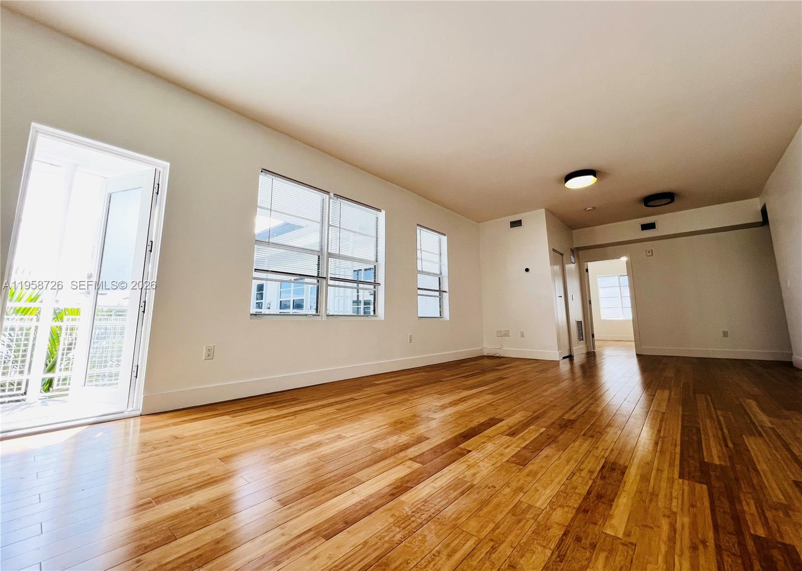960 Bay Drive, Unit 902 Miami Beach, FL 33141 - Photo 3 of 25 an empty room with wooden floor and windows