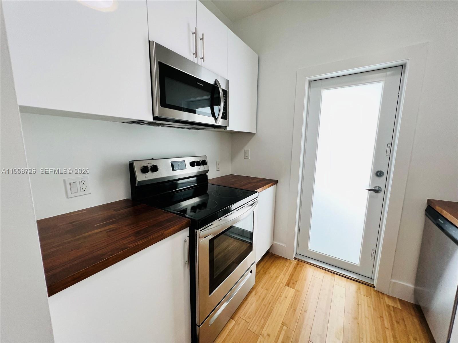 960 Bay Drive, Unit 902 Miami Beach, FL 33141 - Photo 6 of 25 a kitchen with stainless steel appliances granite countertop a sink a stove a microwave and wooden cabinets