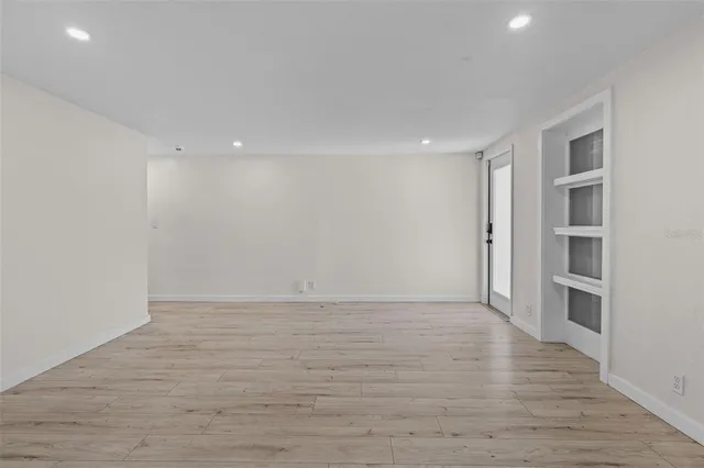a view of an empty room with a window and wooden floor