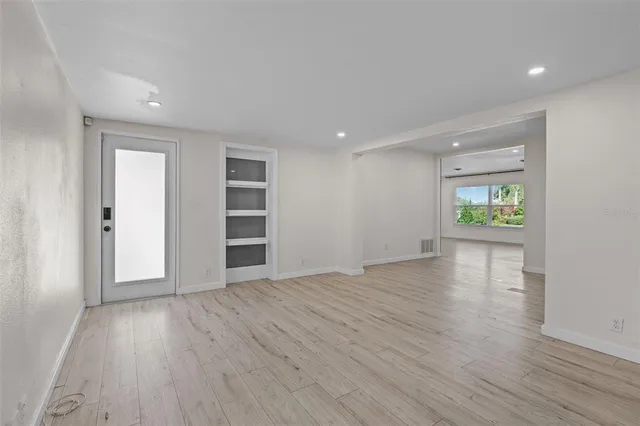 a view of an empty room with wooden floor and a window