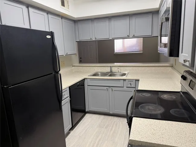 a kitchen with a sink a refrigerator and cabinets