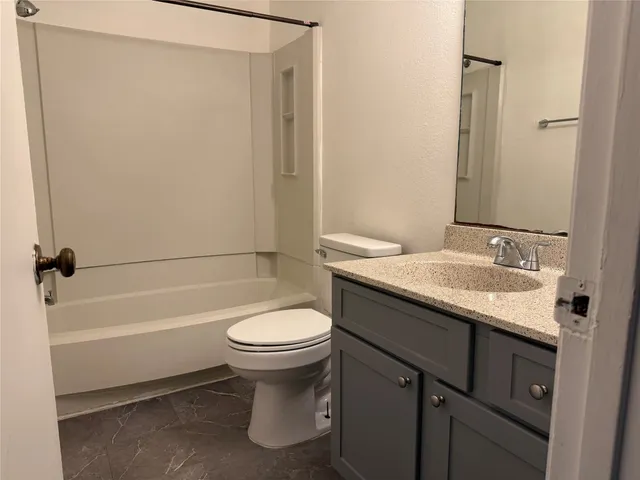 a bathroom with a granite countertop sink toilet and shower