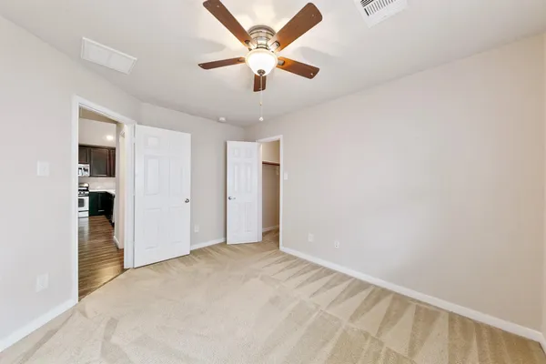 an empty room with closet and a ceiling fan