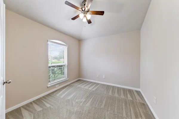 an empty room with a window and a fan