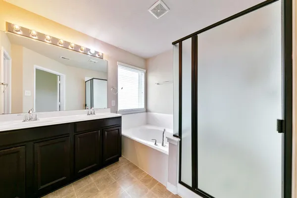 a bathroom with a double vanity sink and mirror with bathtub