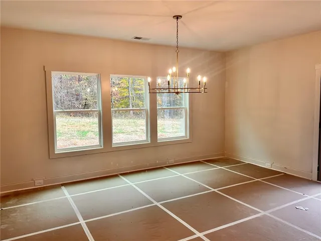 a view of an empty room with windows and chandelier