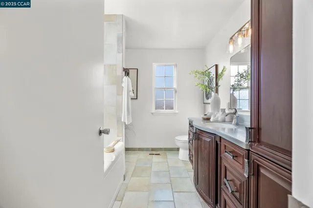 a bathroom with a granite countertop sink a toilet and a mirror