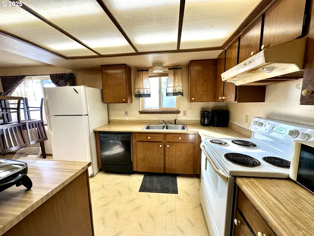 a kitchen with granite countertop a sink a stove and refrigerator